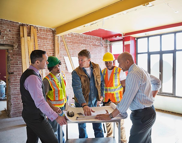 Foreman explaining blueprint to tradesmen at construction site
